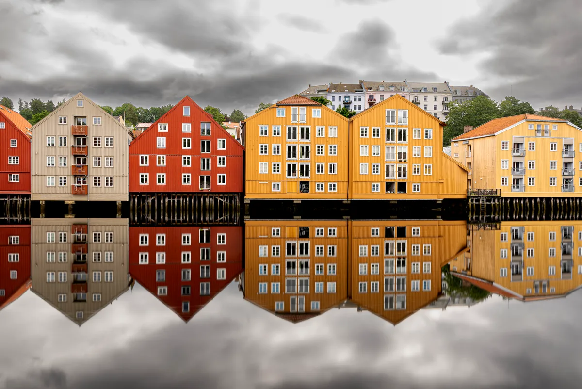 Man sieht einen Kanal gesäumt von farbigen Häusern, die im Wasser reflektieren.